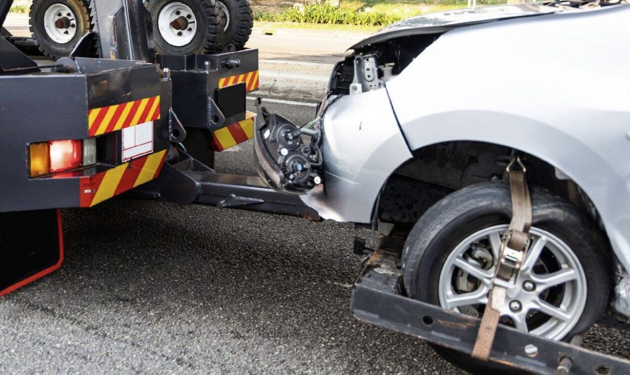 Tow truck operator securing a damaged vehicle for roadside emergency towing in Bay Shore, NY